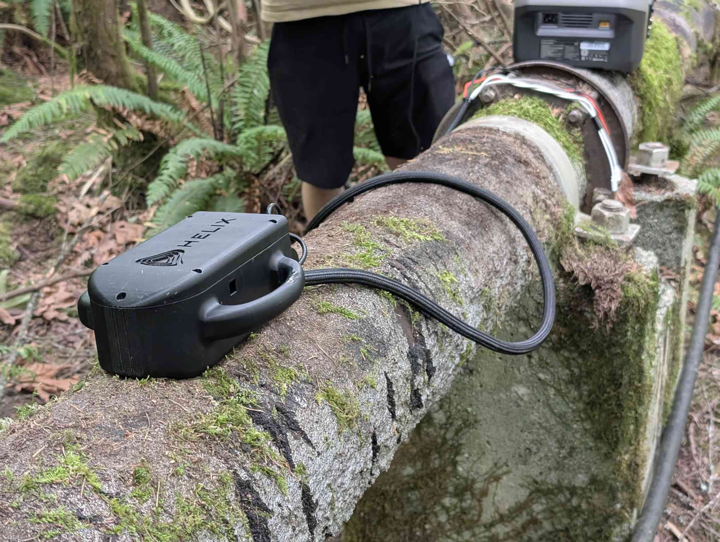 A HELIX pulsed eddy current probe reading wall thickness on an in-service line outdoors, with no insulation removed